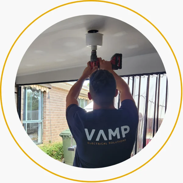 Licensed Vamp Electrical Solutions electrician installing a light fixture in a residential home as part of a guaranteed service