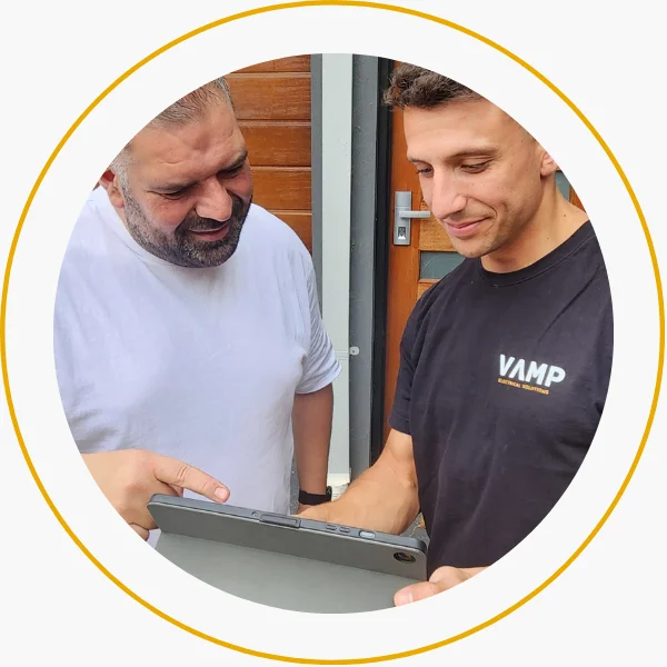 Vamp Electrical Solutions team member discussing project details with a client on a tablet during a booking consultation