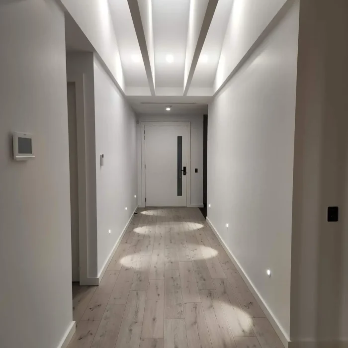 Sleek hallway featuring structural ceiling beams, recessed strip lighting, and low-level step lights in Melbourne
