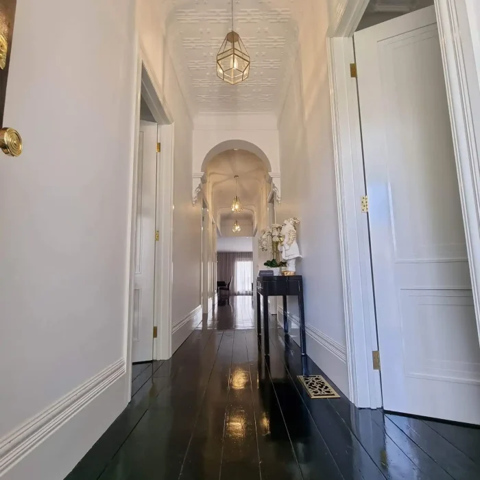 Classic heritage hallway featuring pressed metal ceilings and modern geometric pendant lights in Melbourne