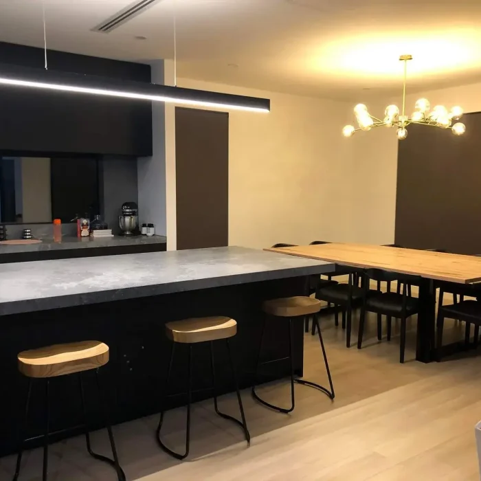 Modern open-plan kitchen and dining area with contemporary pendant and downlight installation in Melbourne
