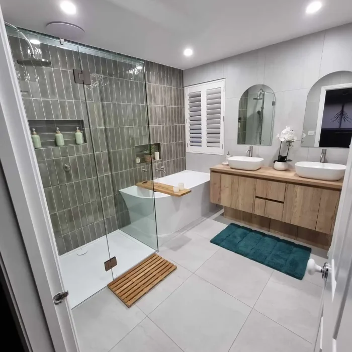 Modern luxury bathroom featuring dual arched mirrors, a freestanding tub, and glass shower in Melbourne