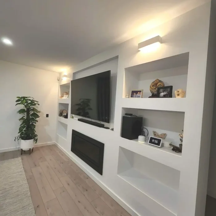 Custom living room entertainment media wall with recessed shelving, TV, and integrated fireplace lighting in Melbourne