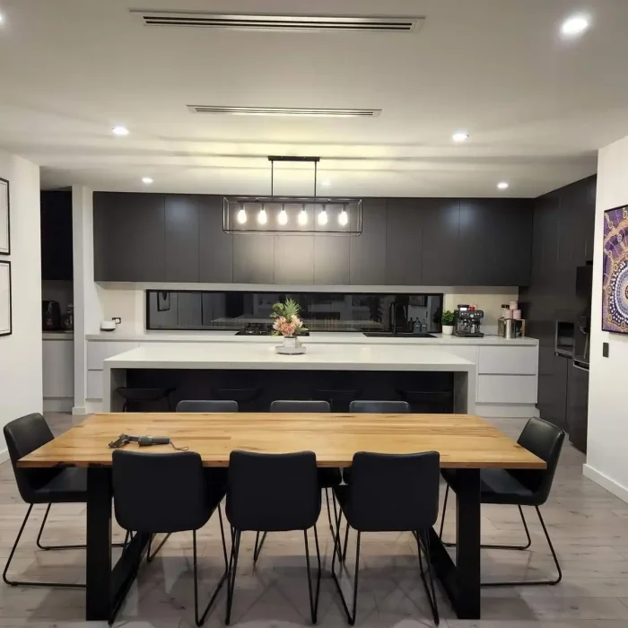 Modern open-plan kitchen and dining area featuring a contemporary pendant light and integrated downlights in Melbourne