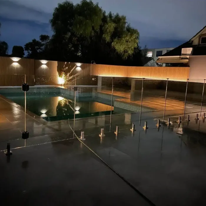 Modern illuminated swimming pool and fence landscaping lighting setup at night in Melbourne